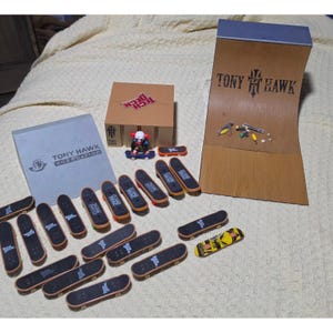 Puede incluir: Una colección de fingerboards Tech Deck y rampas de skate de la marca Tony Hawk. El set incluye una gran rampa de madera tipo half-pipe, una rampa cuadrada, una rampa inclinada gris y numerosos monopatines en miniatura con lija negra y diseños.
