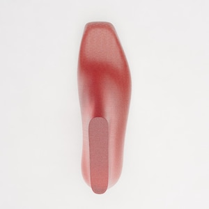 May include: A smooth, reddish-brown shoe tree with a contoured, elongated shape designed to maintain the form of footwear. The object features a solid, rounded toe section and a distinct, slightly darker heel insert on its top surface.