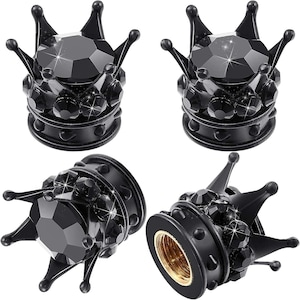 May include: Four black crown-shaped valve stem caps featuring faceted black crystals embedded around the base and top. Each cap has a metallic gold-colored threaded interior for attachment, showcasing a detailed, multi-pointed design.