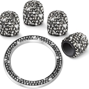 May include: A set of four cylindrical caps and one circular ring, all featuring a dense, sparkling black crystal-like finish. The caps are dome-topped and hollow, while the ring has a smooth silver-toned inner edge and a textured outer surface.