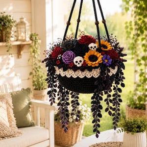 May include: A hanging crochet planter featuring a black bowl with a white scalloped trim, filled with dark red, purple, and yellow crocheted flowers, green foliage, and two small white skulls, suspended by black cords with wooden beads.