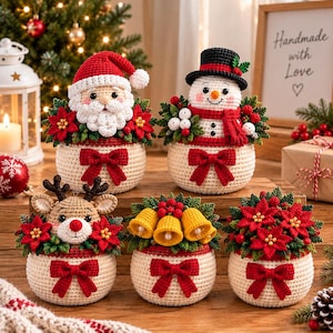 Puede incluir: Cinco decoraciones navideñas de ganchillo que incluyen un Santa Claus, un muñeco de nieve, un reno, tres campanas amarillas y un arreglo de flores de pascua. Cada base redonda es color crema con un lazo rojo, decorada con hojas verdes.