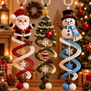 May include: Three hanging crochet ornaments featuring a Santa Claus, a Christmas tree, and a snowman. Each figure is attached to a wooden ring and a long, spiralling crochet tail decorated with small white snowflakes and holly berries.