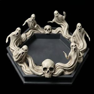 May include: A hexagonal tray featuring a dark gray interior and a raised border decorated with off-white sculpted figures of screaming ghosts and human skulls. The decorative tray has a flat base and a continuous rim adorned with these figures.