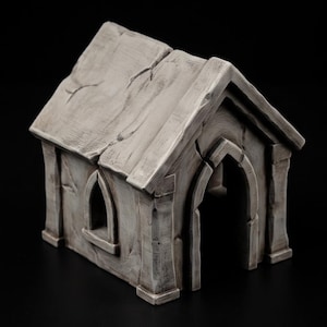 Puede incluir: Una pequeña estructura gris de aspecto pétreo desgastado que presenta un techo a dos aguas con grietas visibles, una puerta de arco apuntado y una ventana arqueada a juego en el lateral. El edificio tiene una textura envejecida con sombras.