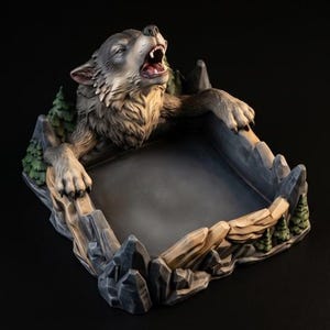 May include: A decorative tray featuring a sculpted gray wolf howling with its paws resting on the edge. The tray base is designed to look like a rocky mountain landscape with small green pine trees integrated into the textured stone walls.