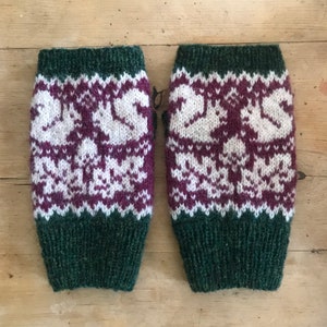 May include: A pair of green, white and purple knitted arm warmers with a snowflake pattern.