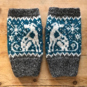 Könnte beinhalten: Ein Paar graue und türkisfarbene gestrickte Handwärmer mit einem weißen Rentiermuster.