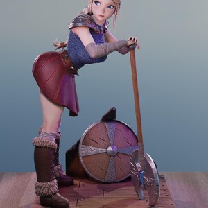 Pode incluir: Uma estatueta estilizada de um guerreiro loiro vestindo um top de cota de malha azul, uma saia vermelha escura e botas marrons com forro de pele. A figura está ao lado de um escudo redondo de madeira e um grande machado de batalha.