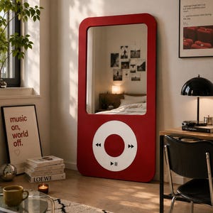 May include: A tall, rectangular floor mirror with a red frame shaped like a vintage digital music player. The mirror features a large white circular control interface at the bottom, complete with black playback symbols for play, pause, and skip.