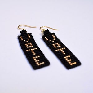 May include: A pair of black beaded earrings with gold lettering that reads "VOTE".