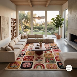 May include: A rectangular area rug featuring a grid of square patches with colourful floral, heart, and rainbow motifs in shades of red, yellow, pink, and green. The rug has a cream-coloured background and includes the text Minahil rugs in the corner.
