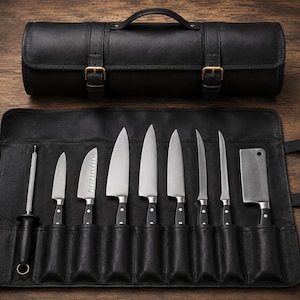 Pode incluir: Um estojo de couro preto para facas contendo oito utensílios de cozinha de aço inoxidável, incluindo uma chaira, várias facas de chef, facas de descascar e um cutelo. O estojo possui fivelas em tom de latão e uma alça superior.
