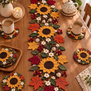 Può includere: Un runner da tavola all'uncinetto con una composizione centrale di girasoli gialli, foglie d'acero rosse e arancioni, margherite bianche, foglie verdi e piccole ghiande. Il set include sottobicchieri all'uncinetto coordinati a forma di girasole.