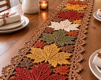 May include: A long, rectangular crochet table runner featuring a repeating pattern of three-dimensional maple leaves in shades of red, orange, yellow, olive green, and cream, bordered by a scalloped brown lace edge with intricate stitching.