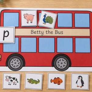 May include: A red bus illustration labelled Betty the Bus with blue windows and black wheels. The set includes a square card with the letter p and six square cards featuring illustrations of a pig, peacock, cow, crocodile, fish, and penguin.