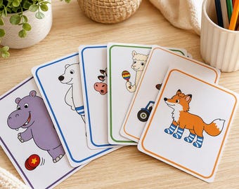 May include: A set of rectangular educational flashcards featuring colorful cartoon illustrations of animals including a purple hippopotamus, a white polar bear, a cow, a llama holding a maraca, and an orange fox wearing blue and white striped socks.