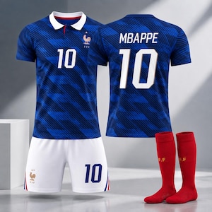 Può includere: Una maglia da calcio blu con colletto bianco, il numero 10 e un emblema di gallo sul davanti. Il retro mostra il nome MBAPPE e il numero 10. Include pantaloncini bianchi con il numero 10 e un gallo, oltre a calzettoni rossi con la scritta F.F.