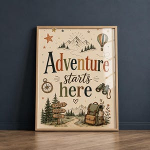 May include: A framed wall art print featuring the text Adventure starts here in colorful lettering. The illustration includes a mountain range, a hot air balloon, a compass, binoculars, a backpack, and a signpost labeled Explore, Discover, Dream.