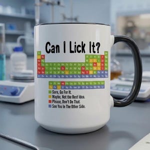 May include: A white ceramic mug with a black handle and rim, featuring a periodic table graphic and the text "Can I Lick It?" followed by a colour-coded legend: "Sure, Go For It," "Maybe, Not the Best Idea," "Please, Don't Do That," and "See You In The Other Side."