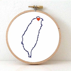 May include: A white embroidery hoop with a blue outline of Taiwan and a red heart in the center.