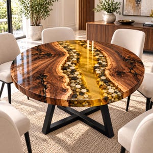May include: A round dining table featuring a polished wood surface with a central river-like inlay of smooth, multicoloured river stones encased in clear, amber-tinted resin, supported by a black metal X-shaped base with four legs.