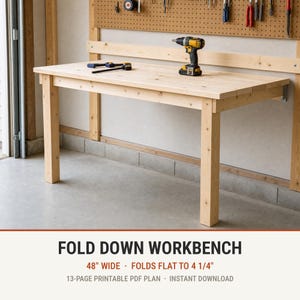 May include: A light-colored wooden fold-down workbench with four legs, mounted to a wall. The workbench features a flat rectangular surface and is shown with a cordless drill and a small tool resting on top. Text reads: FOLD DOWN WORKBENCH 48" WIDE FOLDS FLAT TO 4 1/4" 13-PAGE PRINTABLE PDF PLAN INSTANT DOWNLOAD.