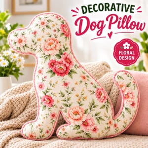 Op de afbeelding: Een hondvormig kussen van crèmekleurige stof met een roze en groen bloemenpatroon. Het kussen heeft roze biezen langs de randen. De tekst op de afbeelding luidt: DECORATIVE Dog Pillow en FLORAL DESIGN in een roze geschulpt embleem.