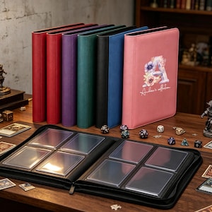 Könnte beinhalten: Eine Sammlung von sechs aufrechten Kartenordnern in Rot, Lila, Blaugrün, Schwarz, Blau und Pink, mit einem offenen schwarzen Ordner mit durchsichtigen Kunststoffhüllen im Vordergrund. Der pinke Ordner zeigt ein florales A und den Text Andrew's collection.