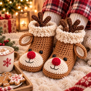Peut inclure: Une paire de chaussons en crochet marron en forme de renne, avec un museau crème, un nez rouge vif, des bois marron foncé et de petites oreilles. Les chaussons présentent un revers texturé couleur crème et sont portés sur des chaussettes blanches.