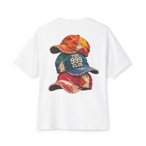 Puede incluir: Una camiseta blanca de manga corta con un estampado gráfico de tres gorras de béisbol desgastadas apiladas. La gorra central es de color verde azulado con el texto THE 999 CLUB en blanco. La gorra superior es naranja y amarilla, la inferior es roja.