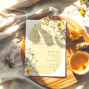 Op de afbeelding: Een gele en witte bloemige babyshower-uitnodiging met de tekst "Mama to be" en de naam "Madelyn Jackson". De uitnodiging bevat ook de datum "07.07.24" en de tijd "RSVP naar 100 Honey Bee Lane, City, State Zip van 13:00 tot 16:00 uur".