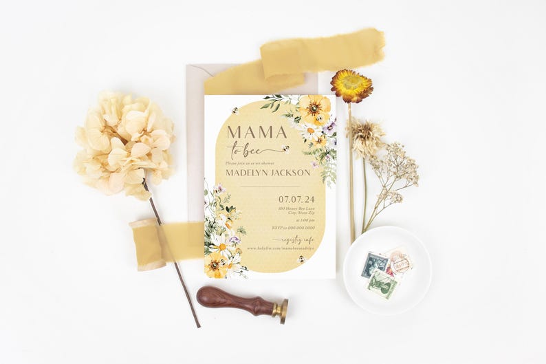 Op de afbeelding: Een gele en witte bloemige babyshower-uitnodiging met de tekst "Mama to bee" en de naam "Madelyn Jackson". De uitnodiging heeft een aquarel-bloemendesign met bijen en een datum van 07.07.24.