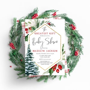 Peut inclure: Une invitation de f&ecirc;te pr&eacute;natale blanche avec un cadre hexagonal dor&eacute;. L'invitation pr&eacute;sente une illustration aquarelle d'un pin enneig&eacute;, du houx et des baies rouges. Le texte indique "The Greatest Gift" et "Baby Shower" en l'honneur de "Madelyn Jackson". L'invitation comprend la date, l'heure, le lieu, les informations RSVP et les d&eacute;tails du registre.