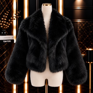 May include: A black faux fur cropped jacket featuring long sleeves and a wide, plush collar. The garment is displayed on a mannequin, showcasing a thick, textured pile throughout the entire piece with a consistent dark black colour and open front.