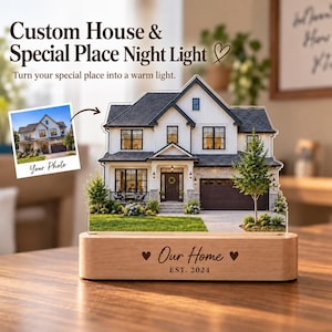May include: A custom night light featuring a printed image of a two-story house on a clear acrylic panel. The light sits on a rectangular wooden base engraved with the text "Our Home" and "EST. 2024" flanked by two small heart symbols.