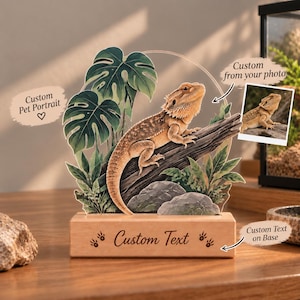 May include: A custom acrylic pet portrait featuring a bearded dragon perched on a log, surrounded by green monstera leaves and rocks. The display sits on a rectangular wooden base with the engraved text Custom Text and small paw prints.