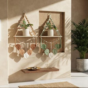 May include: Two wall-mounted macrame shelves featuring wooden planks, braided cord hangers, and dangling leaf-shaped fibre accents. One shelf displays brown and white leaves, while the other features sage green and white leaves, each holding a white ribbed pot.