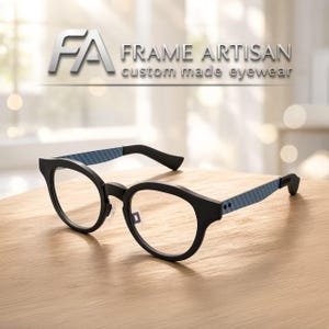 May include: Black eyeglasses with a matte finish and blue textured temples. The frame features a rounded shape and clear lenses. Above the glasses, the text reads FA FRAME ARTISAN custom made eyewear in a clean, modern font style.