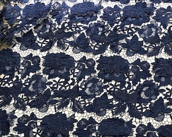 May include: Navy blue lace fabric with a floral pattern. The lace is delicate and intricate, with a repeating design of flowers and leaves.