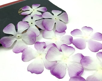 May include: Purple and white paper flower petals. The petals are layered with a gradient of color, starting with a light purple at the edges and fading to white in the center. The petals are delicate and have a soft, velvety texture.