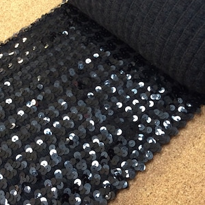Puede incluir: Tela negra con lentejuelas con un respaldo negro. Las lentejuelas son redondas y tienen un ligero brillo iridiscente.