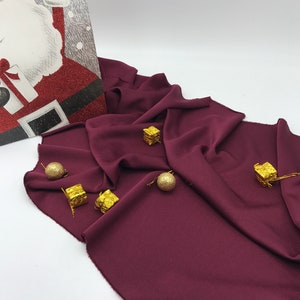 Peut inclure: Une toile de fond en tissu bordeaux avec des ornements décoratifs dorés. Les ornements sont en forme de petites boîtes avec une surface texturée.
