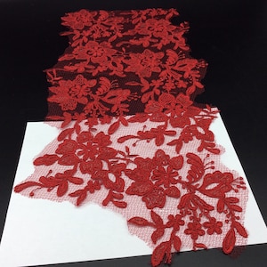 May include: Red lace fabric with a floral pattern. The lace is delicate and intricate, with a fine mesh background.
