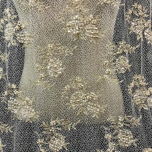 K&ouml;nnte beinhalten: Nahaufnahme eines beigefarbenen Spitzenstoffs mit floraler Stickerei. Die feine Netzstruktur ist mit detaillierten, erhabenen Blumenmustern verziert. Die Stickerei ist in einem helleren, schimmernden Ton gehalten und erzeugt ein strukturiertes und elegantes Aussehen.