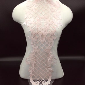 Op de afbeelding: Een delicate roze kant applique met een bloemenpatroon en een rasterpatroon. De kant is perfect om een ​​toets van elegantie toe te voegen aan elk project.