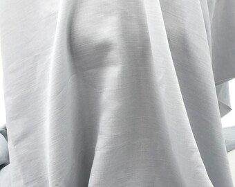 May include: A light gray fabric with a smooth, slightly textured surface. The fabric is draped and folded, showcasing its soft and flowing nature.