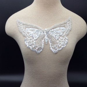 Può includere: Un'applicazione a forma di farfalla bianca con paillettes e perline. L'applicazione è perfetta per aggiungere un tocco di brillantezza a vestiti, borse o decorazioni per la casa.