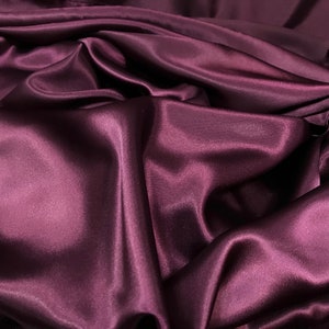 May include: Close-up of a deep purple satin fabric, showing its smooth, silky texture and soft folds.