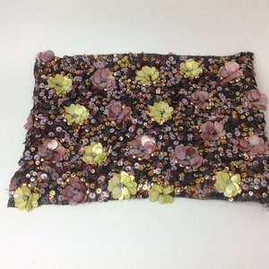 Peut inclure: Un tissu de près avec un fond noir recouvert de paillettes et de petites fleurs en relief dans des tons de rose, or et vert.